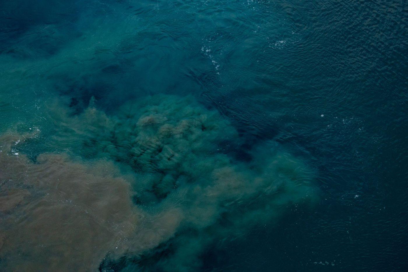 Aerial view of turbid, discolored water spreading in plumes across the ocean surface